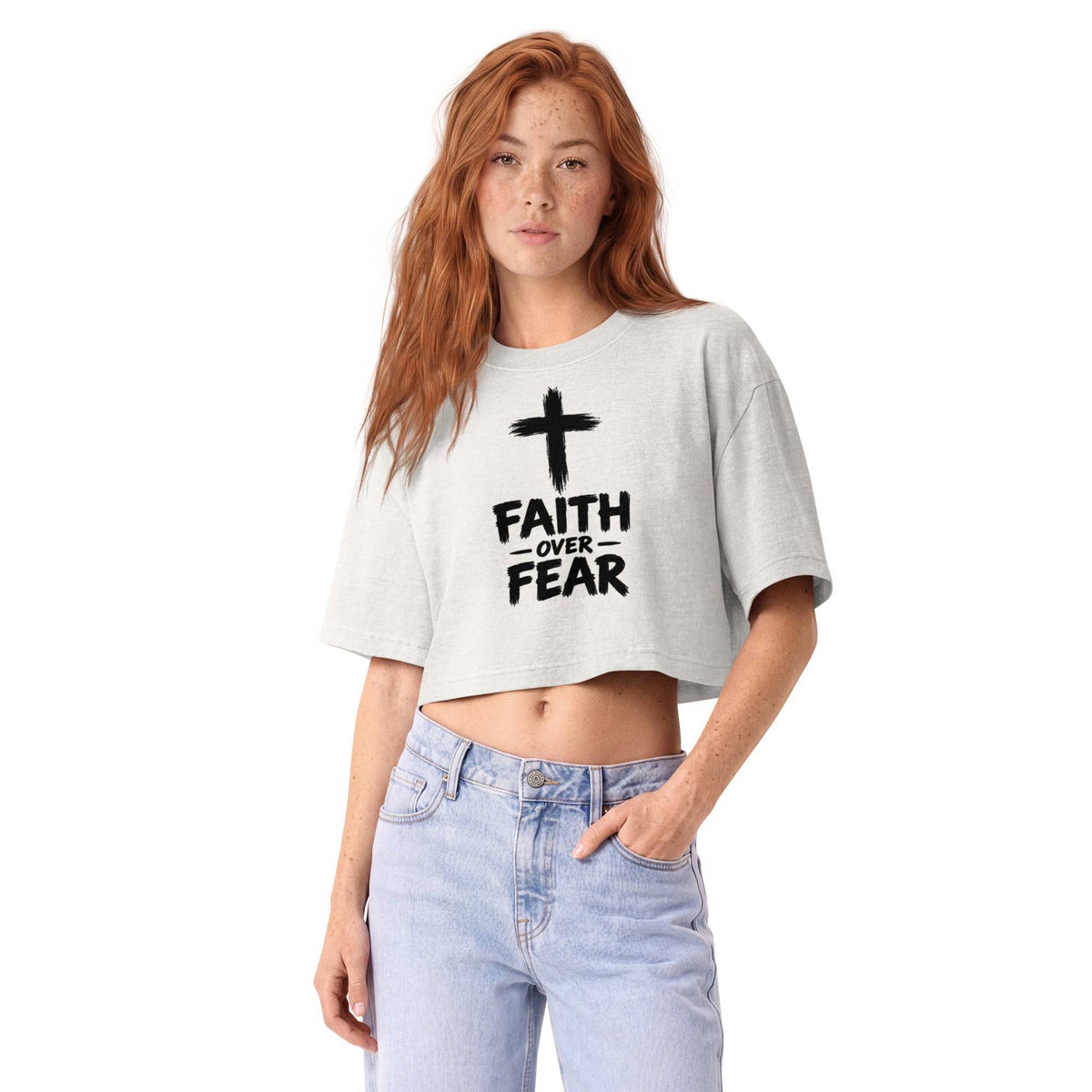Women wearing a light gray garment-dye cropped t-shirt with a black cross graphic and 'Faith Over Fear' text, paired with light blue jeans, casual streetwear style